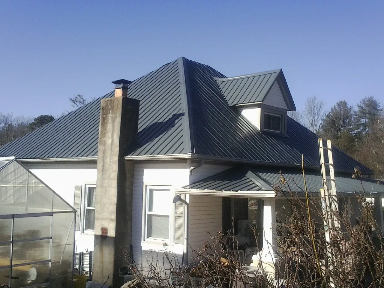 Dark blue standing seam metal roof on a white farmhouse with dormer — Slate & Tile Roof Repair by Roofing Brothers in Runnemede