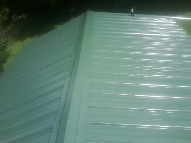 New green metal panels meeting at the ridge of a roof — Flat Roof Repair work by our crew in Runnemede