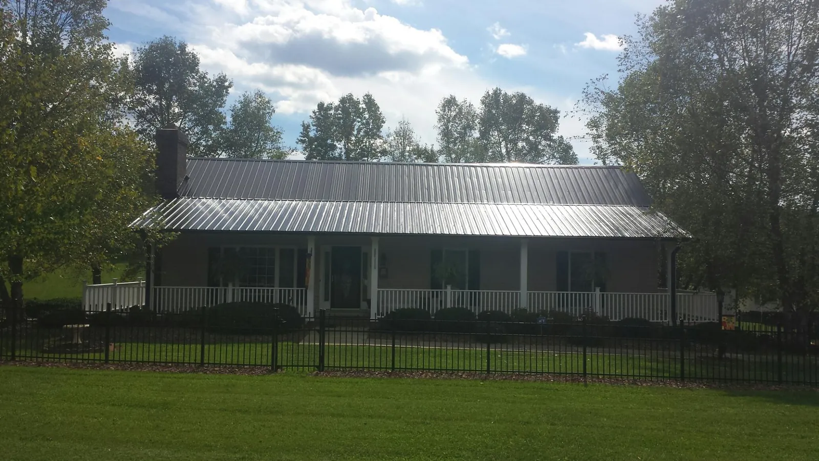Gray metal roof on a brick ranch with a full width front porch — Gutter Guard Installation work by our crew in Runnemede